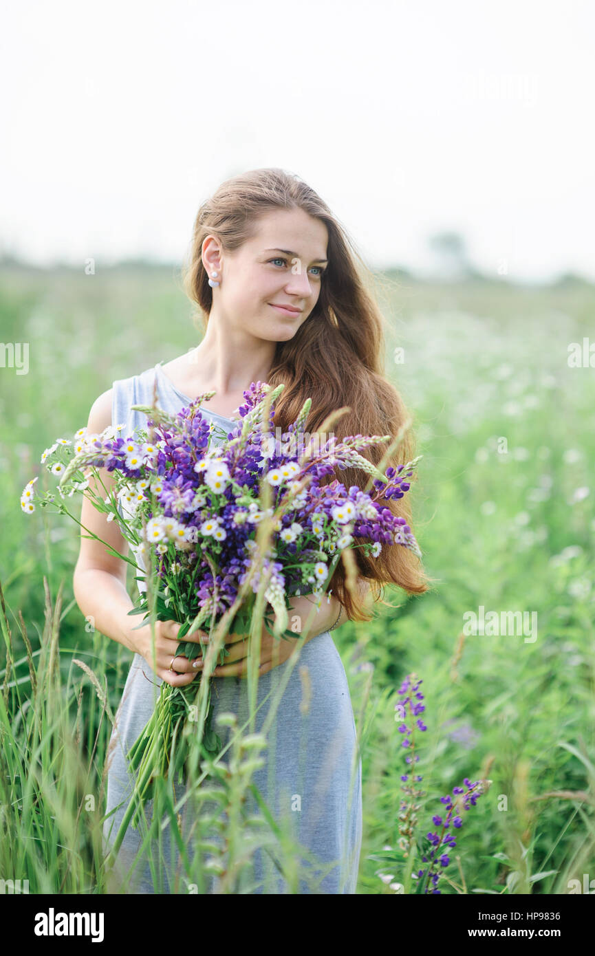 beautiful young woman with a bouquet of flowers on the summer meadow Stock Photo