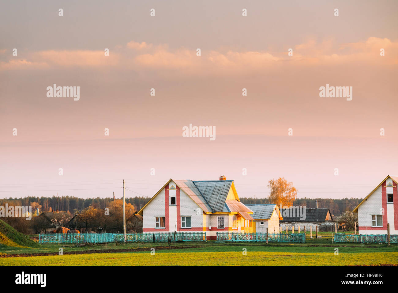 Typical Belarusian Or Russian Brick House In Village Or Countryside Of Belarus Or Russia Countries At Sunset Or Sunrise. Spring Or Summer Season Stock Photo