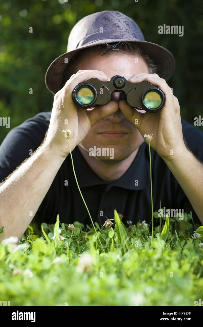 Model released , Junger Mann mit Fernglas in der Wiese - man with spy glass  in meadow Stock Photo - Alamy