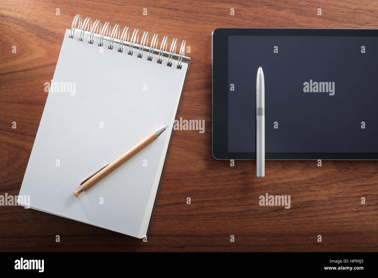 Stripped notepad and pencil vs tablet and digital pen. Analog and digital. Stock Photo