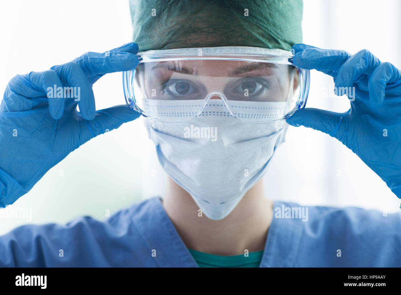Female surgeon preparing for the surgical operation and wearing protective glasses, healthcare and safety concept Stock Photo