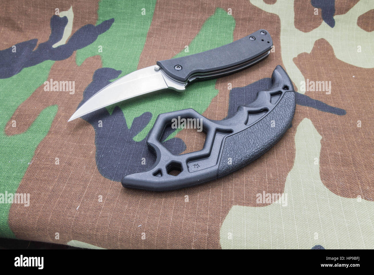 https://c8.alamy.com/comp/HP9BFJ/knife-and-brass-knuckles-on-a-camouflage-background-tools-for-self-HP9BFJ.jpg