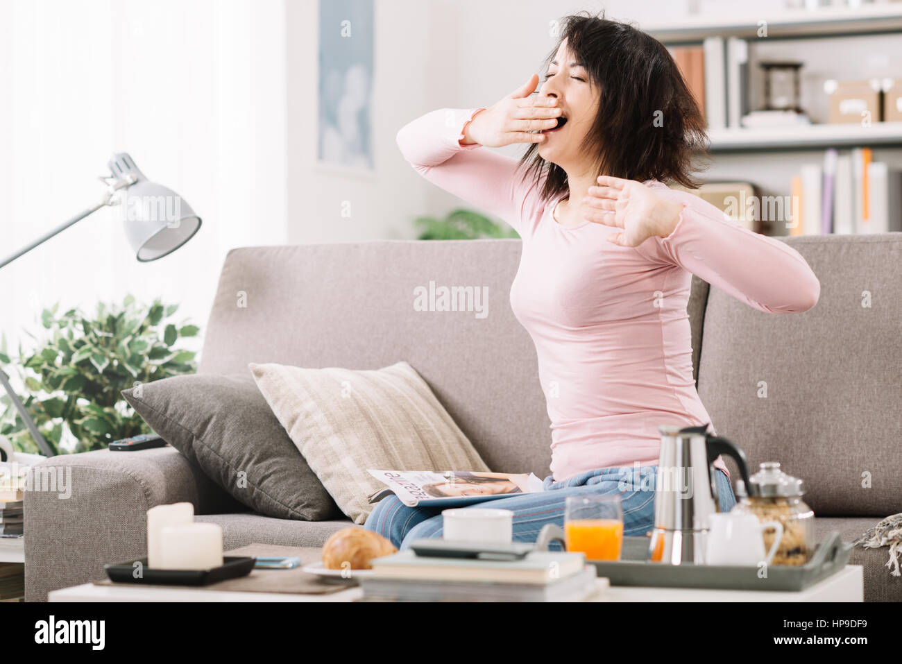 Young woman at home waking up after a bad night's sleep on the couch