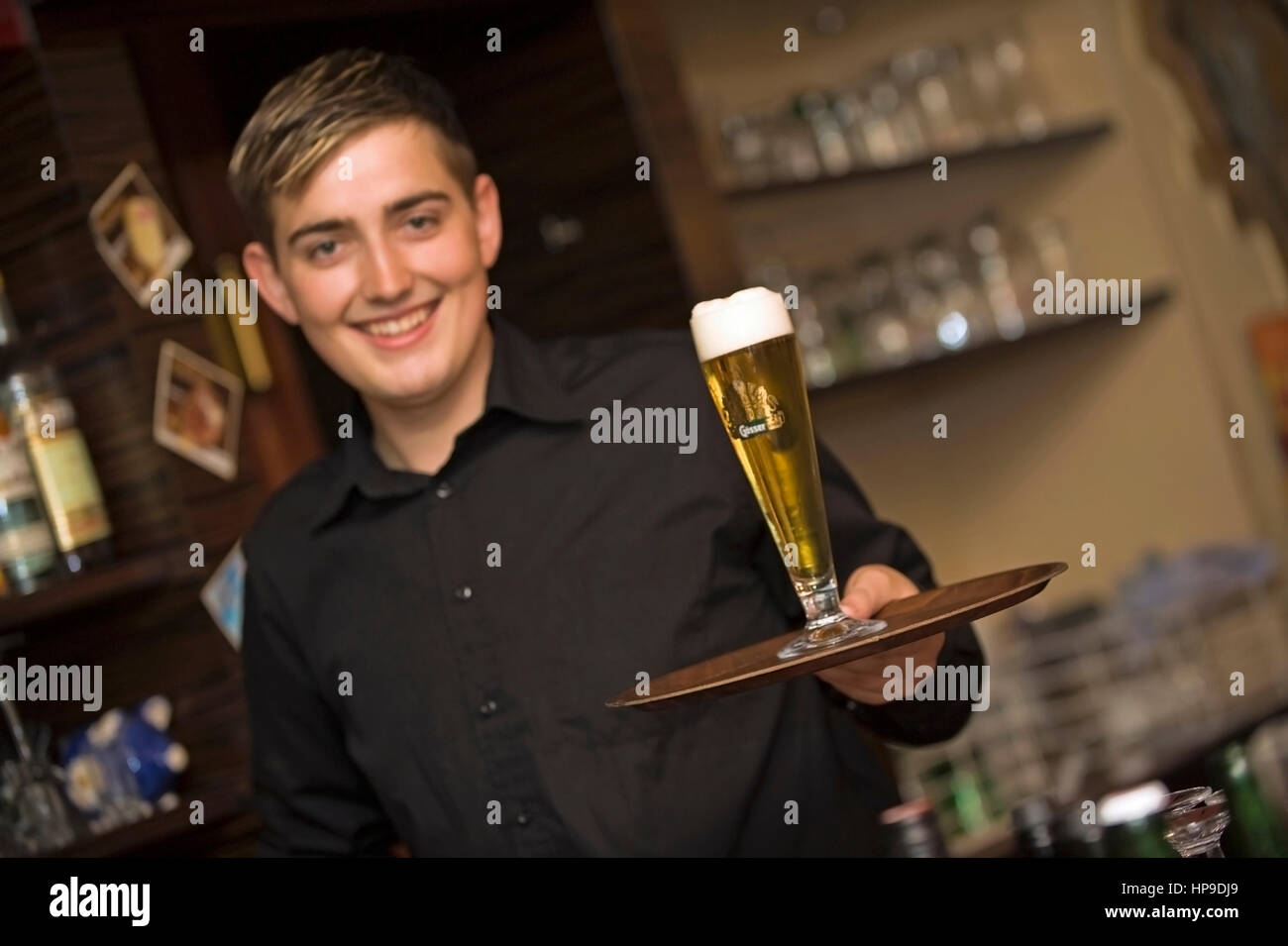 Model released , Junger, freundlicher Kellner mit Bierglas am Tablett - waiter served beer on a tablet Stock Photo