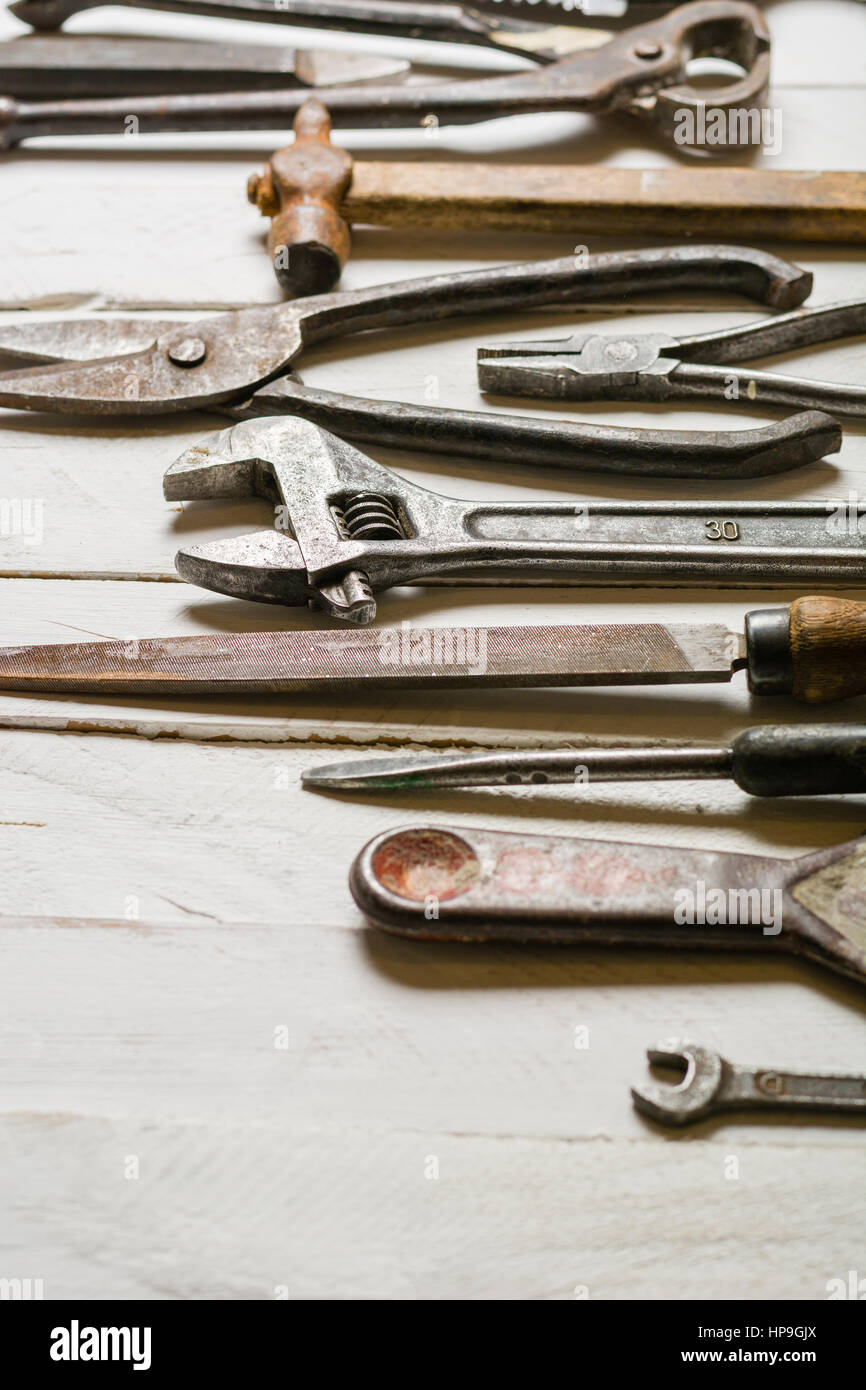 Many old rusty tools scattered on the wooden tstolu. View from above ...