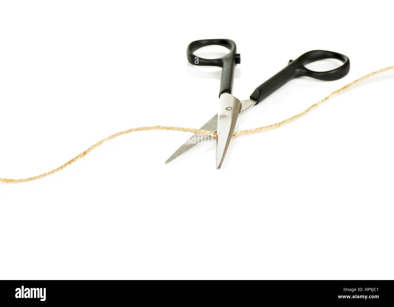 Pair of Scissors Cutting a Length of Brown String Isolated on White Background Stock Photo