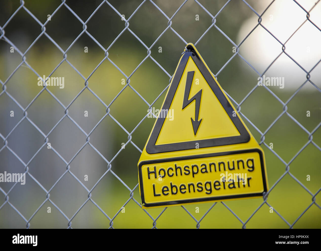 Gelbes Warnschild Hochspannung Lebensgefahr, an Zaun Stock Photo