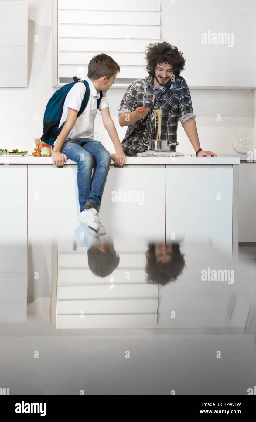 Happy father preparing meal to son in kitchen. Father preparing son for school Stock Photo