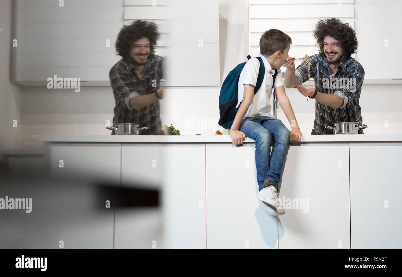 Happy father preparing meal to son in kitchen. Father preparing son for school Stock Photo