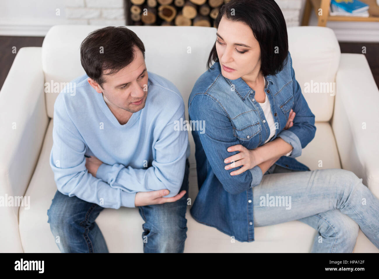 I do not talk with you. Angry cheerless nice couple sitting back to back and crossing their arms while having a quarrel Stock Photo