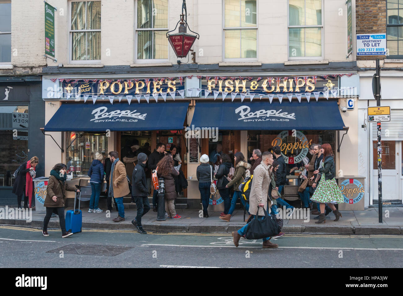 A busy street scene with customers and passers-by outside Poppies fish and chip shop, Hanbury Street, London E1. Stock Photo