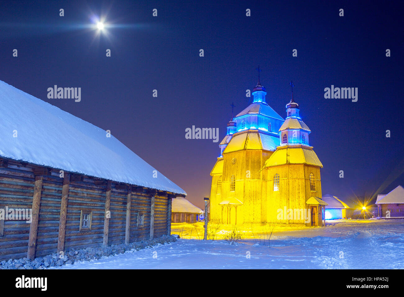 Winter night on cossacks fortress 'Zaporizka Sich' with illuminated wooden church and shining Moon, Khortytsia island, Zaporozhye, Ukraine Stock Photo