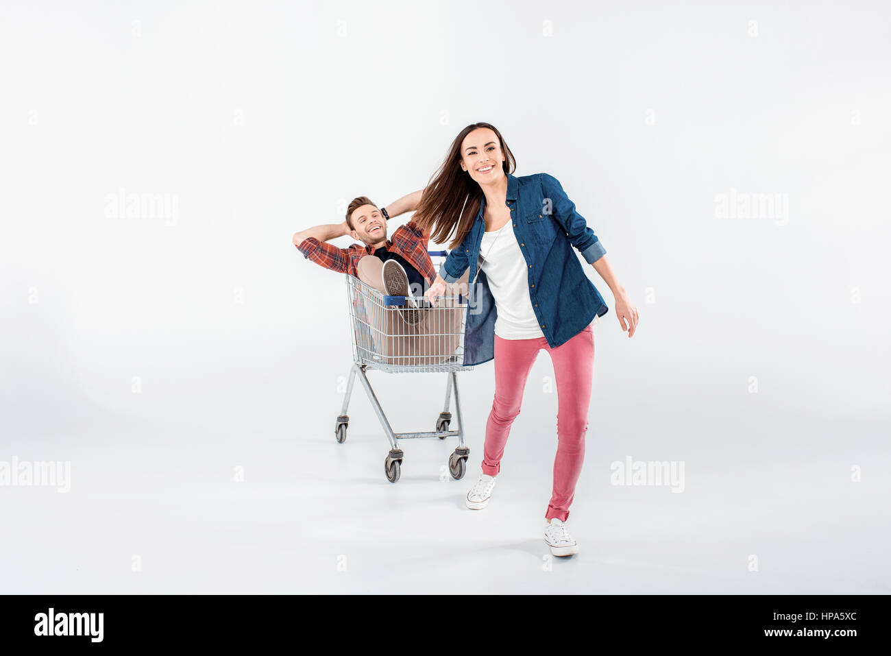 woman carrying happy man in shopping cart on white Stock Photo Alamy