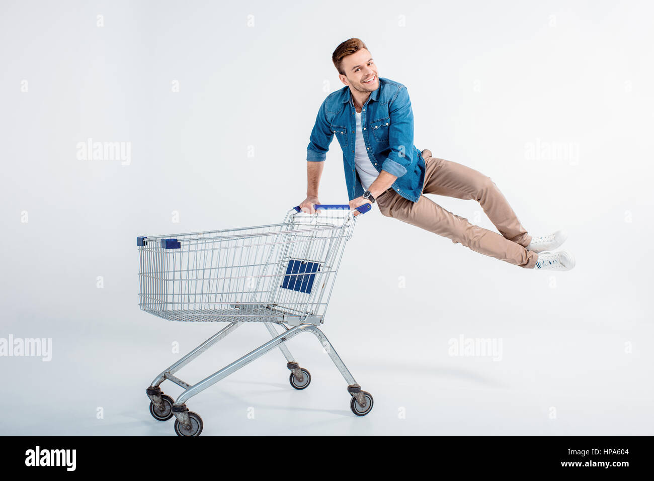 man jumping and having fun with shopping trolley on white Stock Photo
