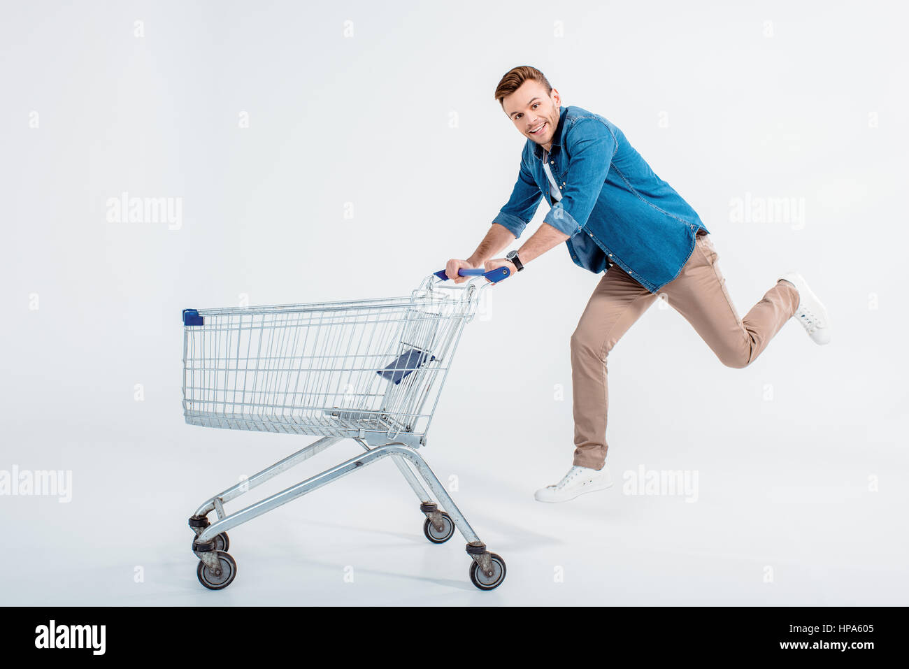 man running with shopping trolley and smiling at camera Stock Photo