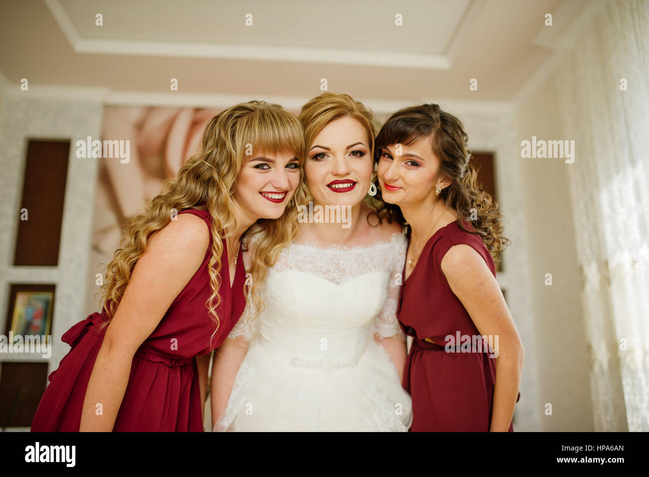 Smilling bride with bridesmaids on red dresses indoor room Stock Photo ...