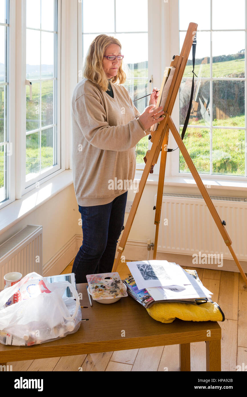 Woman painting in bright, daylight studio. Stock Photo