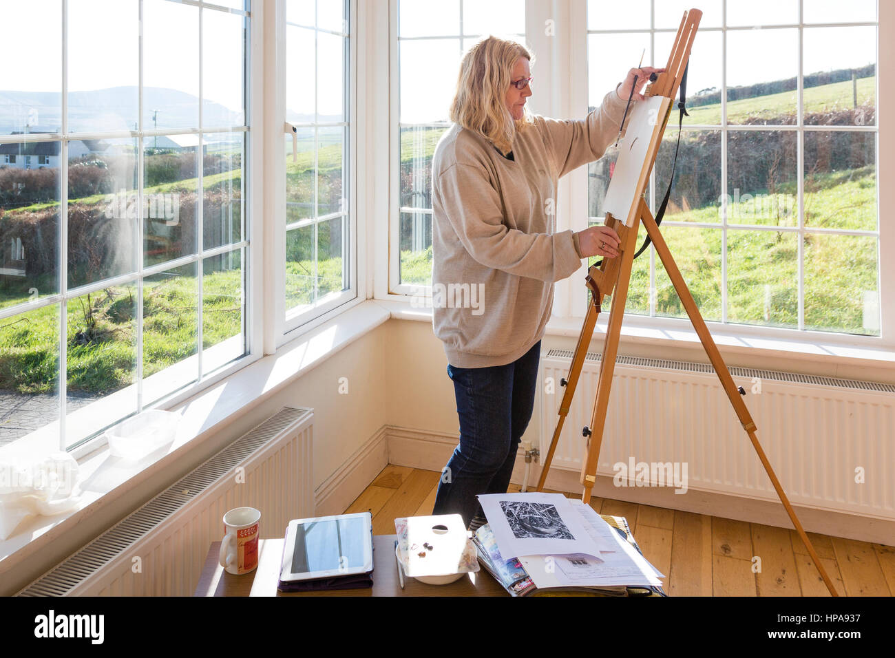 Woman painting in bright, daylight studio. Stock Photo