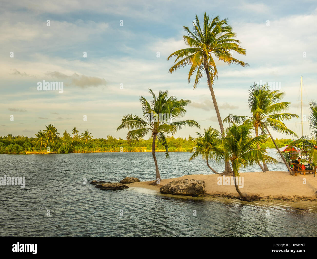 Island at Camana Bay in the Caribbean  with people sitting on sun loungers in the late afternoon, Grand Cayman, Cayman Islands Stock Photo