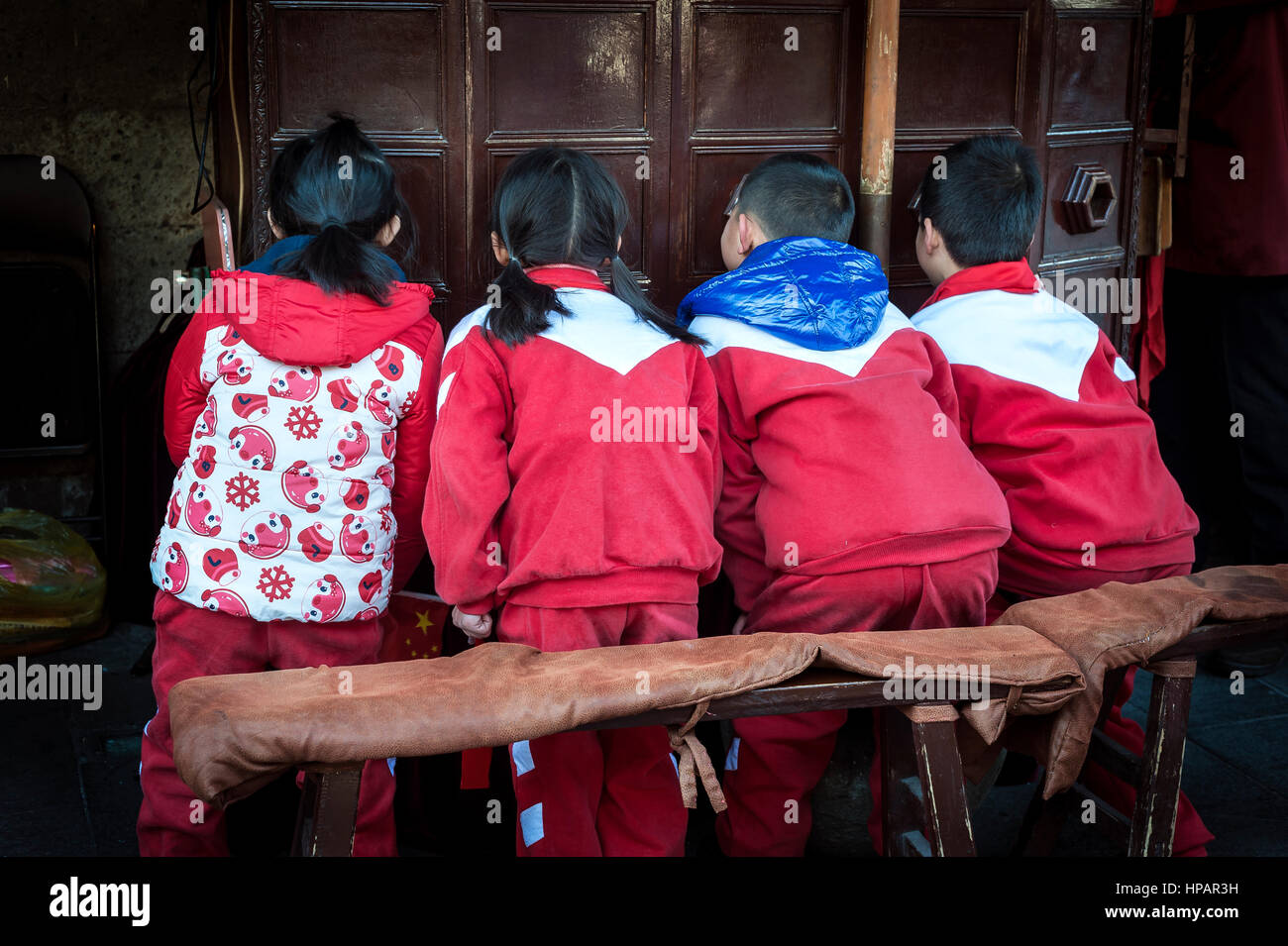 HANGZHOU, CHINA - FEB 2015 - A group of school children watch an old movie through a wooden box on Hefang Old Street in Hangzhou, China Stock Photo