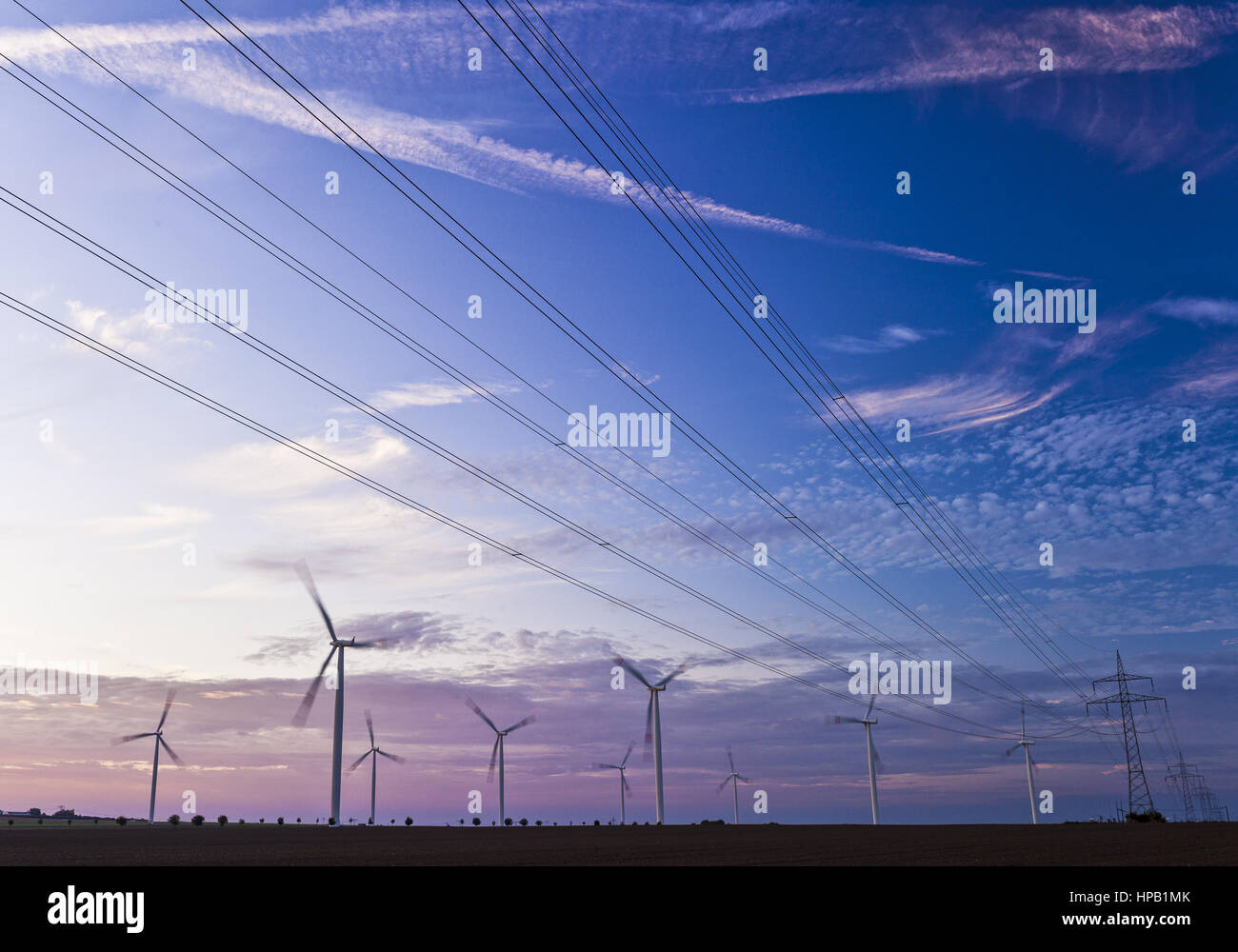 Windkraftturbinen und Ueberlandleitungen im Morgenlicht Stock Photo