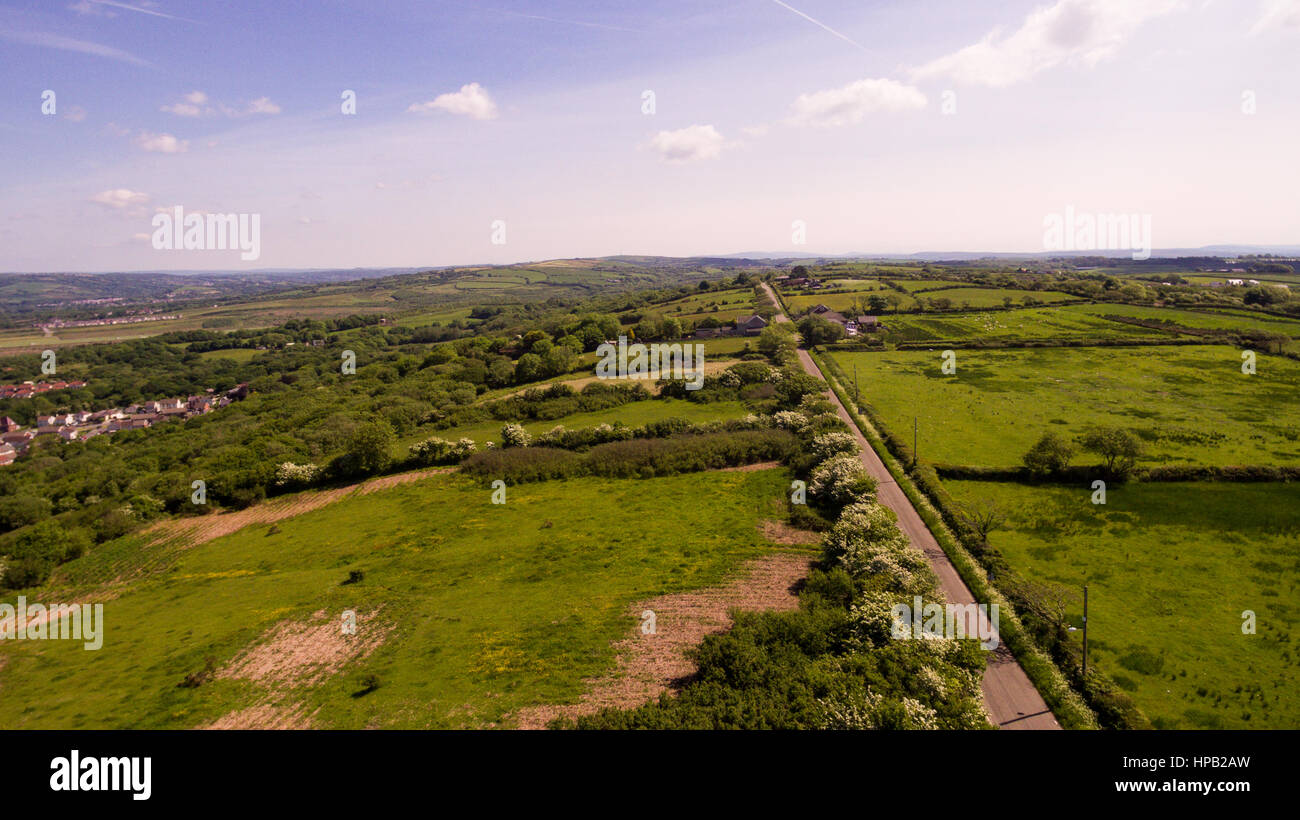 Aerial views of a lush green countryside with blue skies overhead Stock Photo