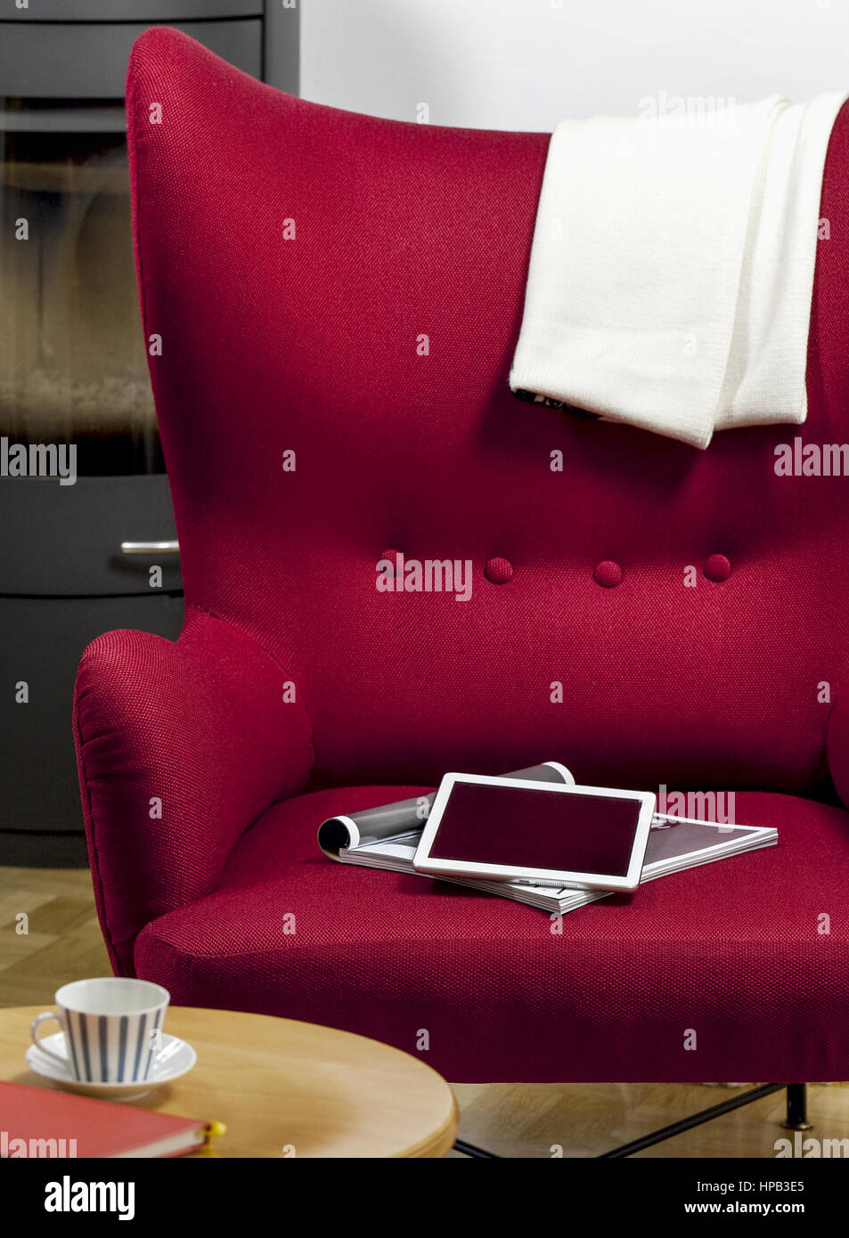 Tablet-PC und Zeitschrift liegen auf rotem Sessel Stock Photo