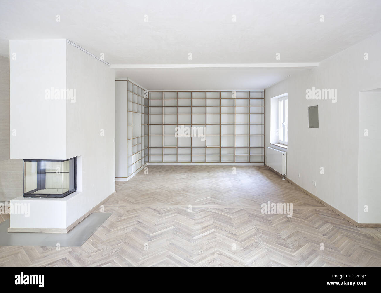 Leerer weisser Wohnraum mit Parkettboden und Regalwand Stock Photo