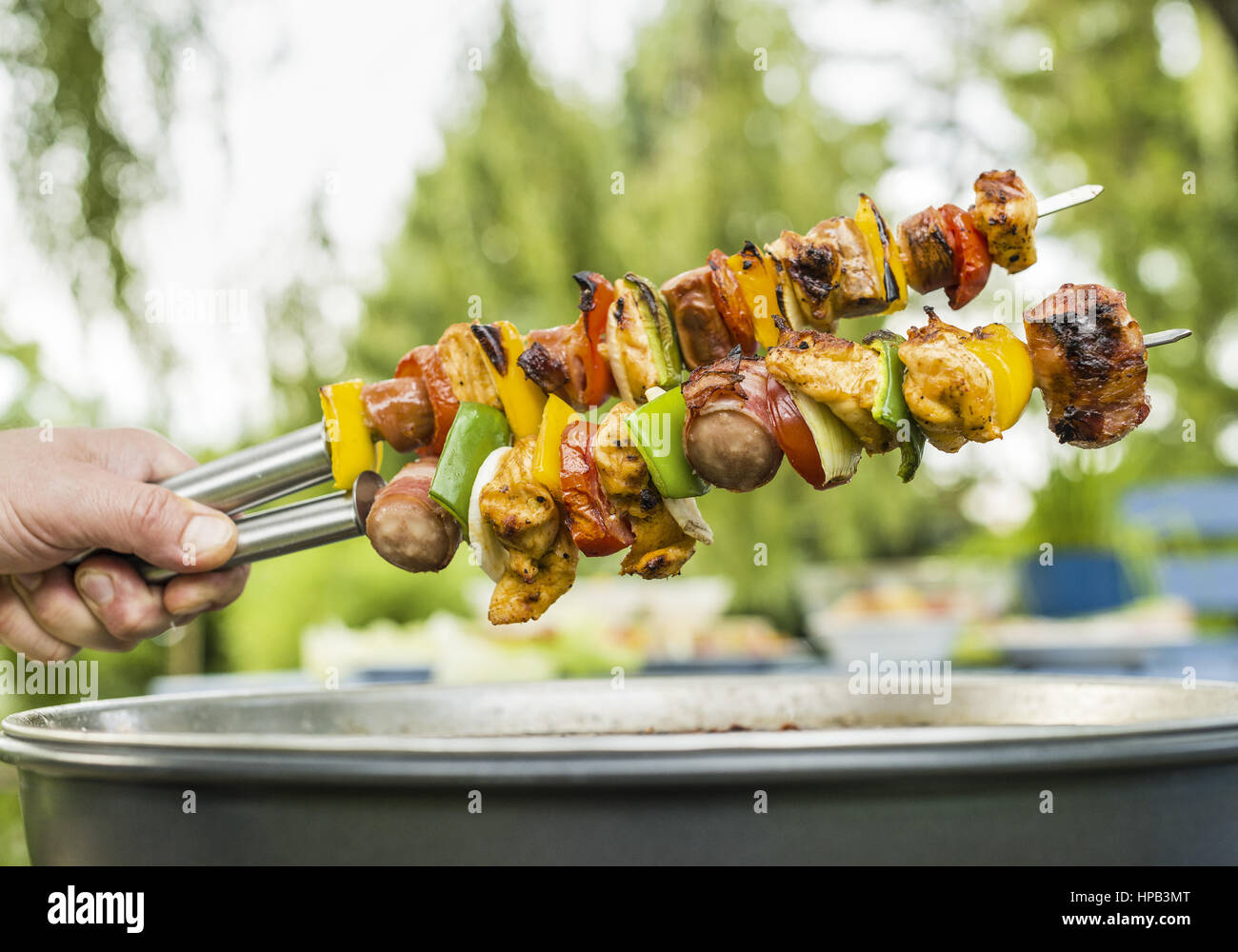 Grillspiesse werden ueber Grill gehalten Stock Photo