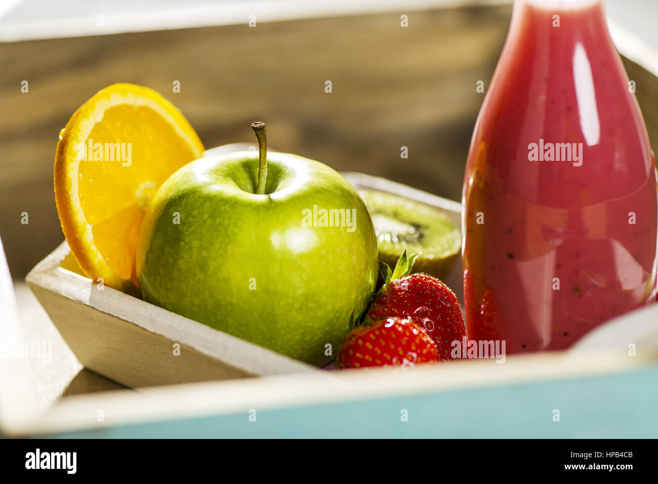 Fruchtsmoothie in Glasflasche und Obst in Holzschale Stock Photo