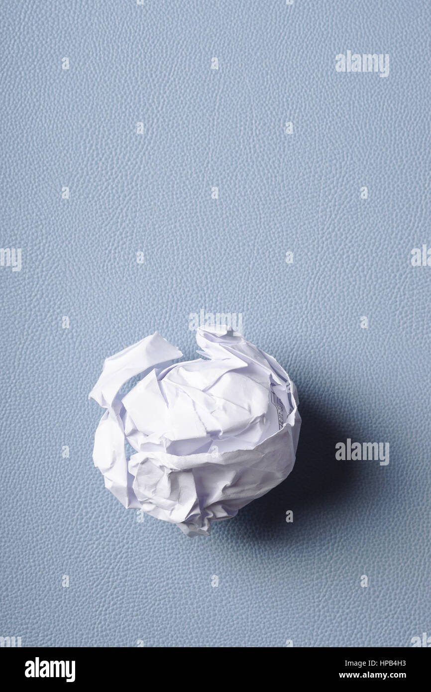 crumpled-up ball of paper on blue background Stock Photo