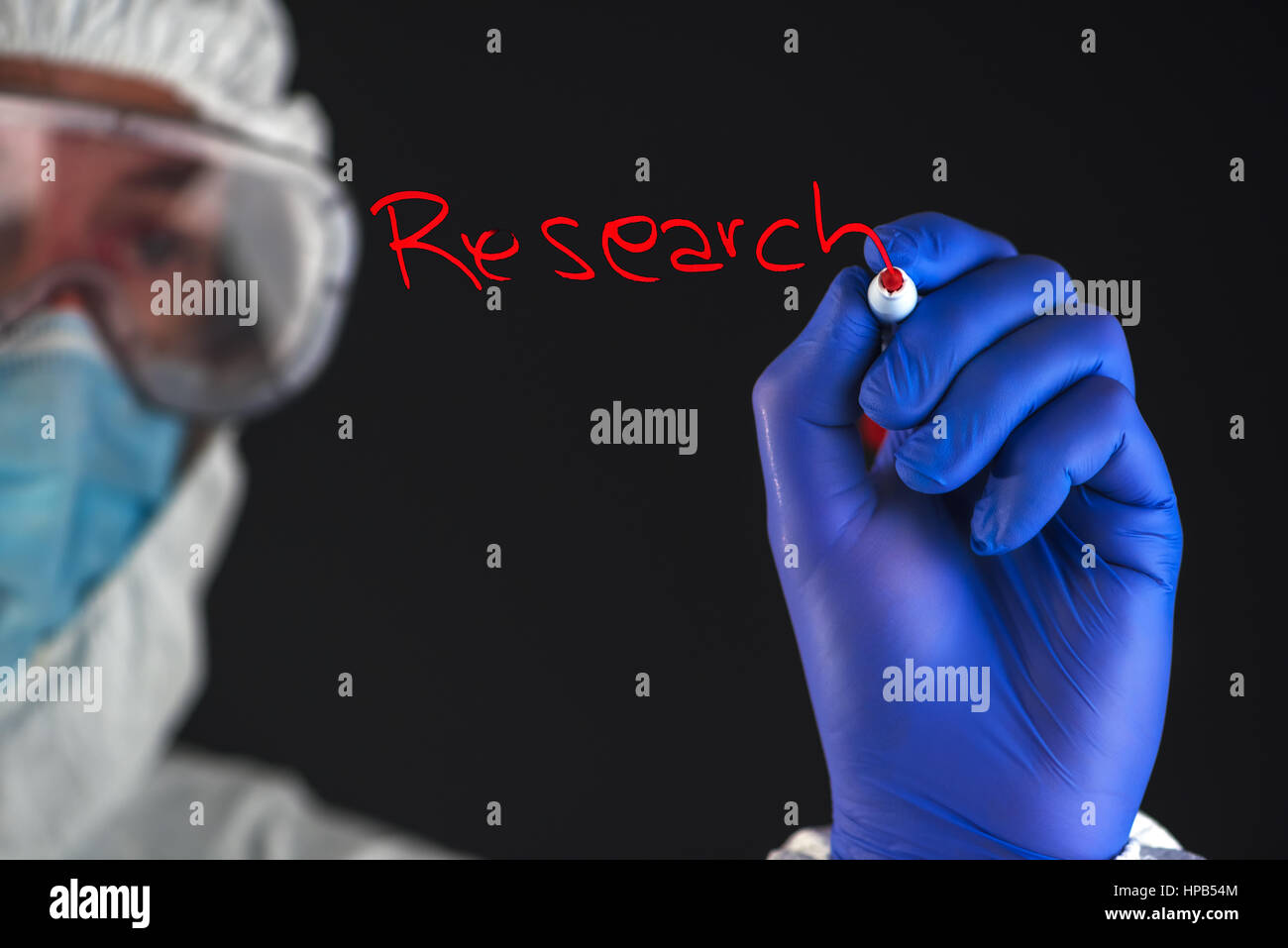 Scientist in protective clothes writing Research with red marker felt tip pen Stock Photo