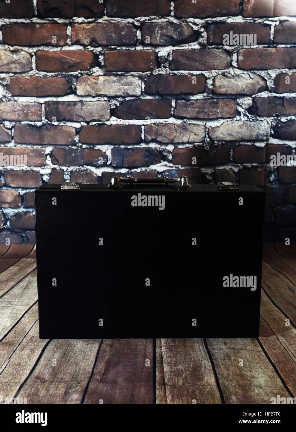 Black suitcase on brick wall background. Black case on wooden floor. Small suitcase for business papers Stock Photo