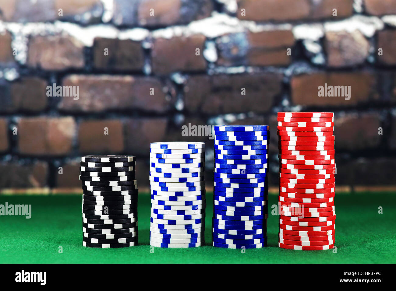 Columns of poker chips on green poker table. Close up color  chips on brick background. Perfect online games concept Stock Photo