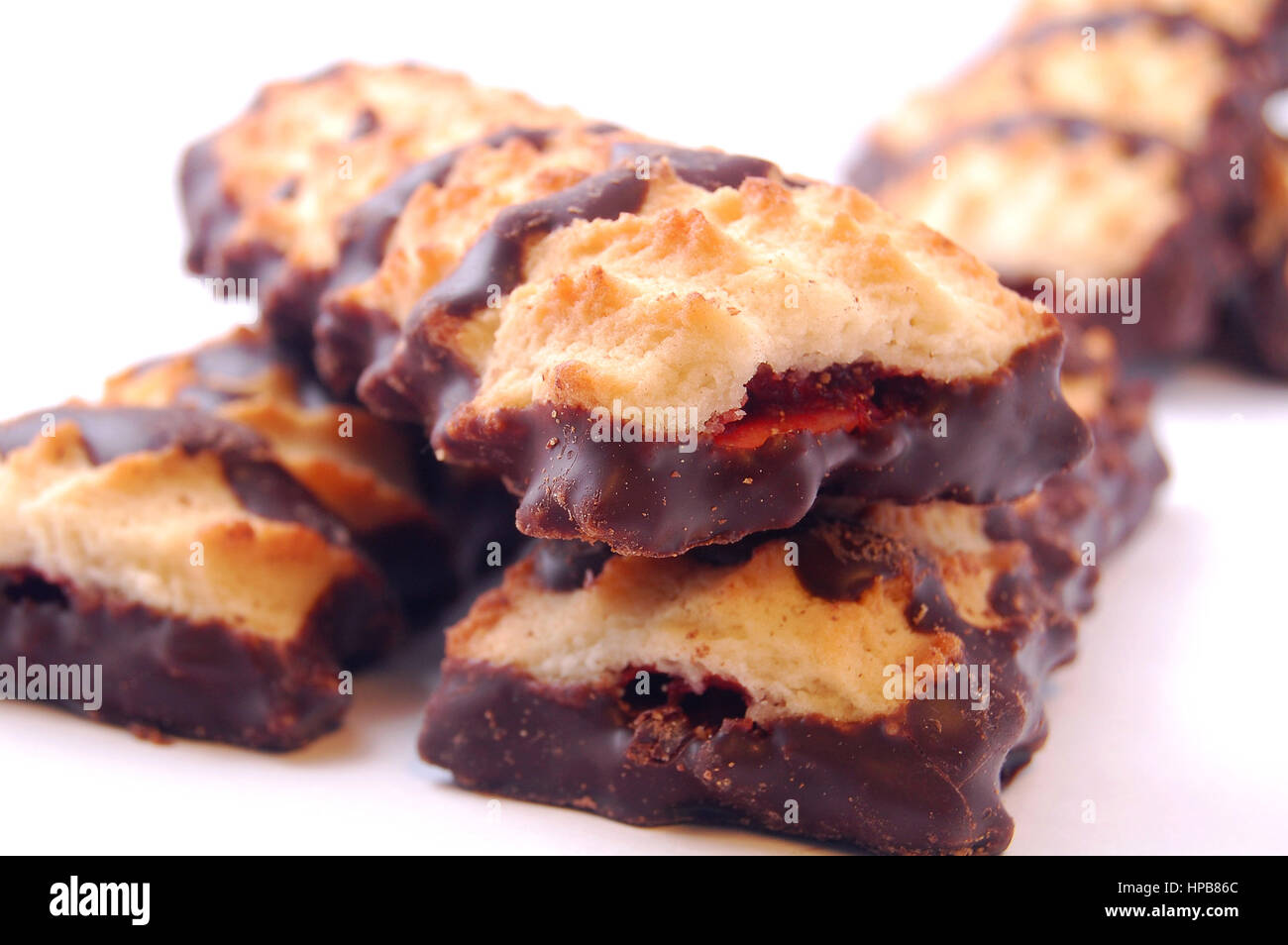 Pile of shortbread cookies with jam and chocolate icing on white background. Stock Photo