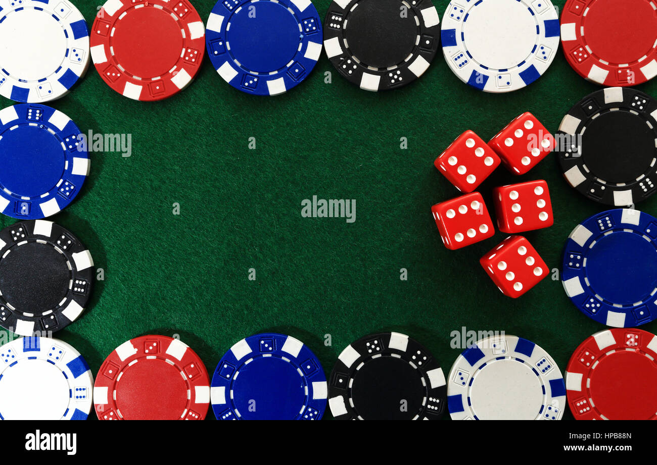 Framing of poker chips on green gaming table. Red dice inside frame of game chips  close up. Online game background. Casino chips on green textured ba Stock Photo
