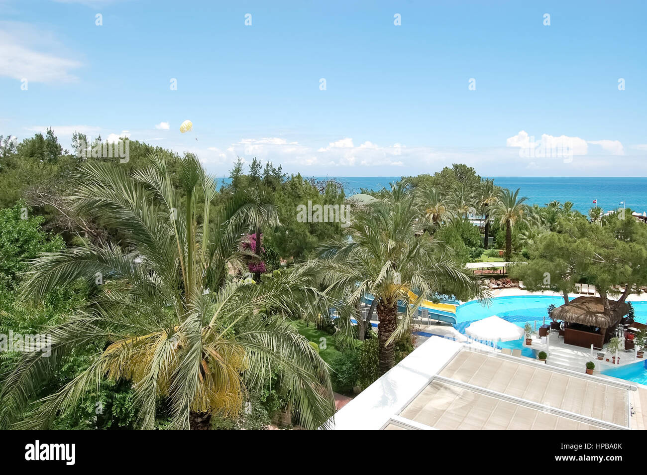 A view of a green garden, a swimming pool, a poolside bar and blue sea in the hotel of high class  on the Mediterranean resort in Turkey. Stock Photo
