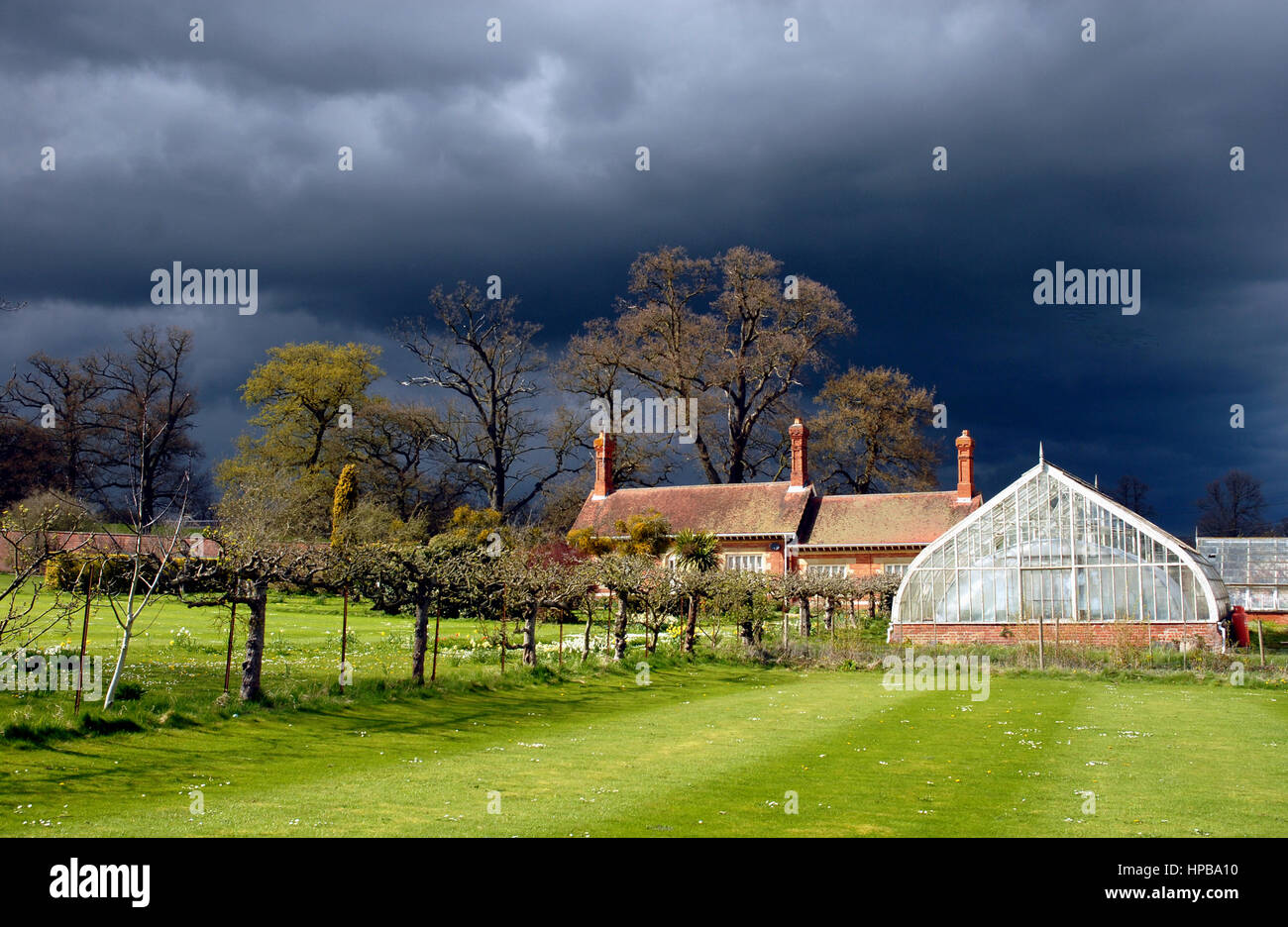 Grimsthopre Castle kitchen gardens with a Victorian glasshouse, espaliers and with impending storm Stock Photo