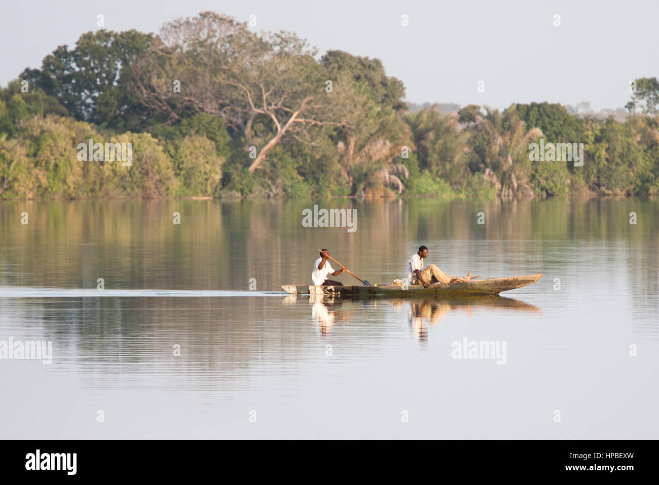 Locals fish with nets in a handcrafted dug out canoe on the River Gambia Stock Photo