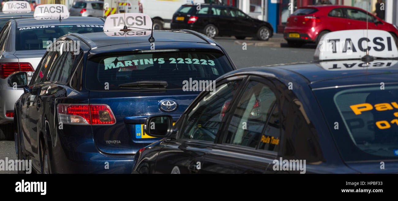 Taxis for hire waiting on a street in Carmarthen, displaying the Welsh word Tacsi Stock Photo