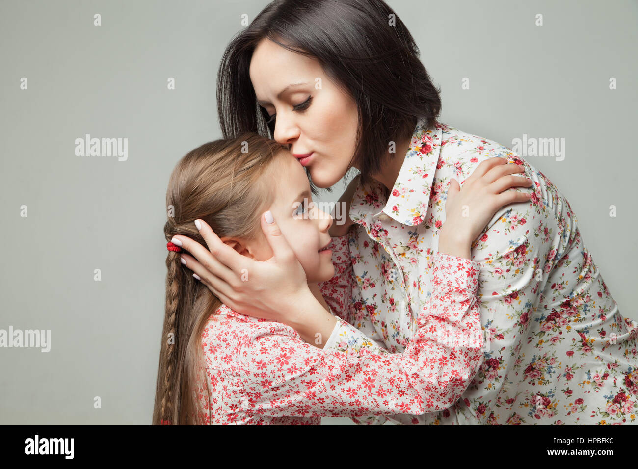 Beautiful and happy young mother kissing her small daughter Stock Photo - Alamy