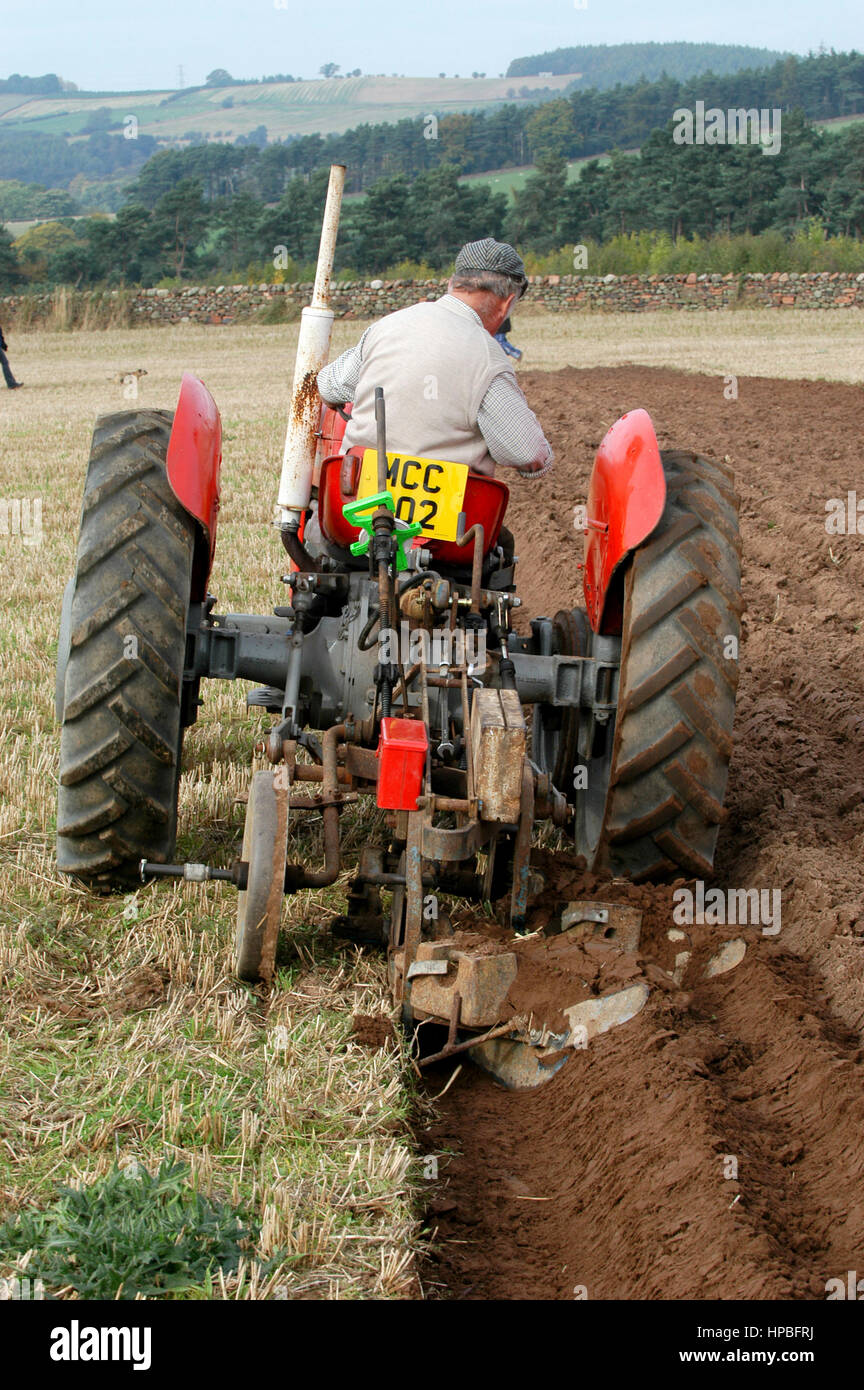 Farmer on a vintage tractor ploughing with a 2 furrow plough at a ploughing competition, Cumbria, UK. Stock Photo