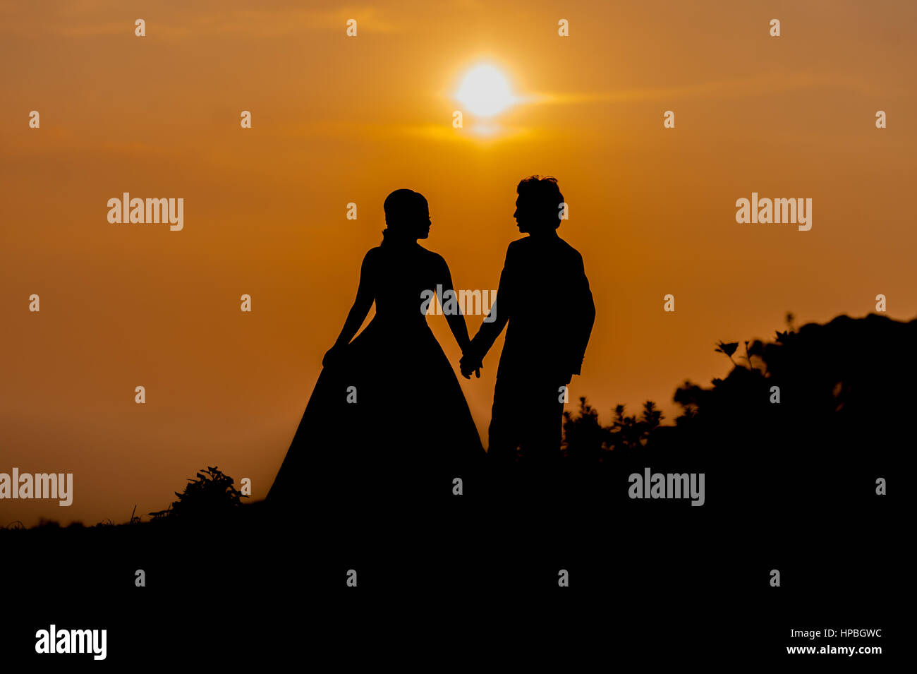 Silhouette of Asian Bride and Groom Standing on Mountain at Sunset ...