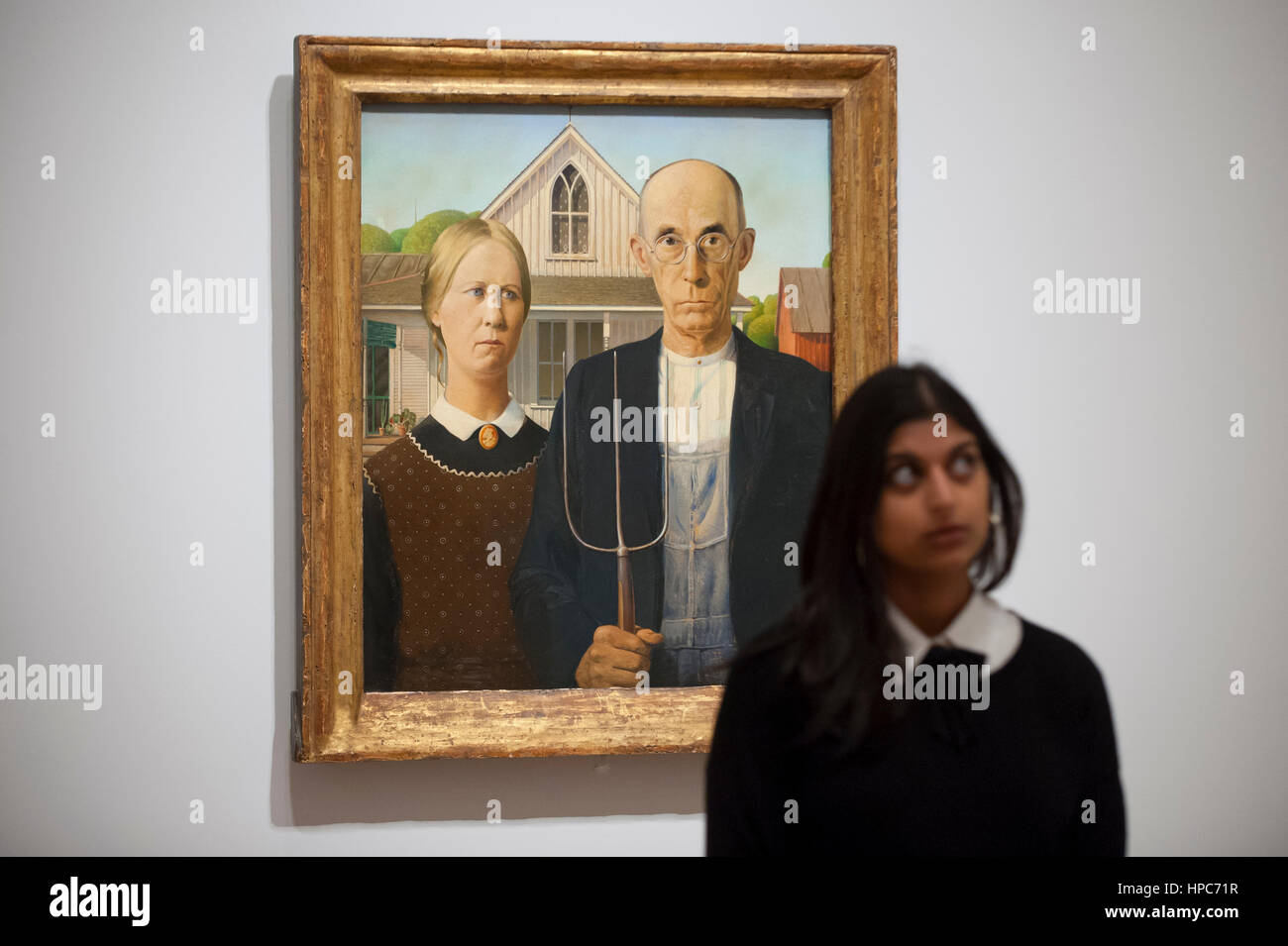 London, UK. 21st Feb, 2017. A staff member stands with 'American Gothic', 1930 by Grant Wood, at the preview of 'America after the Fall: Painting in the 1930s', an exhibition of 45 seminal paintings chronicling the impact of the decade following the Wall Street Crash of 1929. Credit: Stephen Chung/Alamy Live News Stock Photo