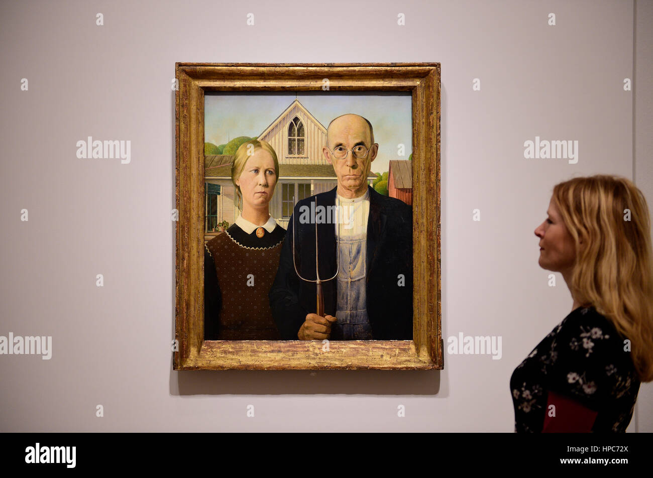 Royal Academy, London, UK. 21st Feb, 2017. America after the Fall: Painting in the 1930's, an exhibition chronicling the turbulent economic and political climate dominating the decade after the Wall Street Crash of 1929. Included in the exhibition is the iconic painting ‘American Gothic' by Grant Wood (photo), posed with a member of gallery staff, seen outside of America for the very first time, and works by Edward Hopper, Georgia O'Keefe, Jackson Pollock and Thomas Hart Benton. Credit: Malcolm Park editorial/Alamy Live News Stock Photo