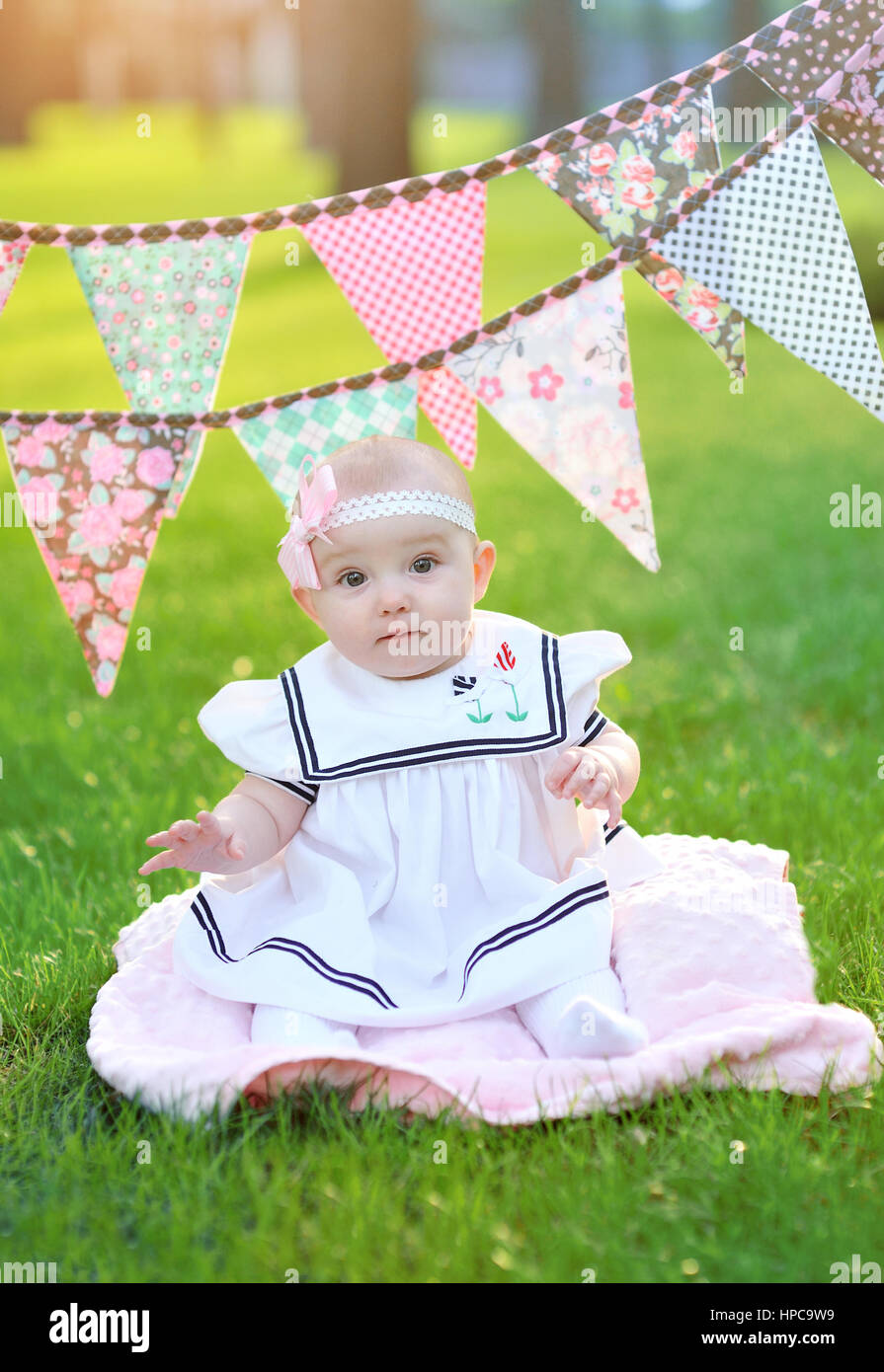 little girl in white dress sitting on the grass in the park Stock Photo ...