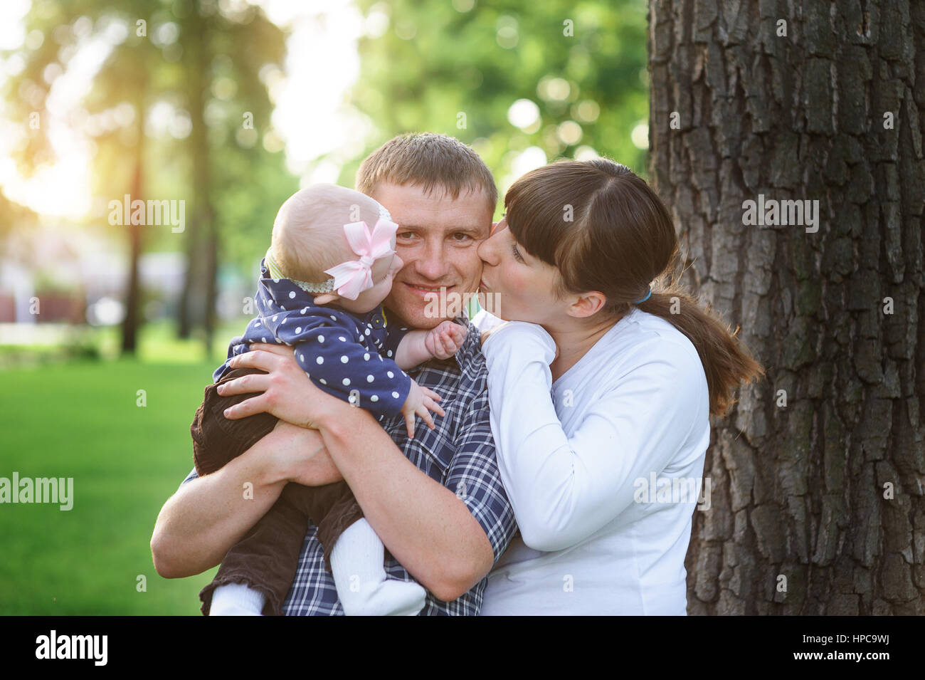 happy family in the park in spring sunny day kissing of daddy Stock Photo