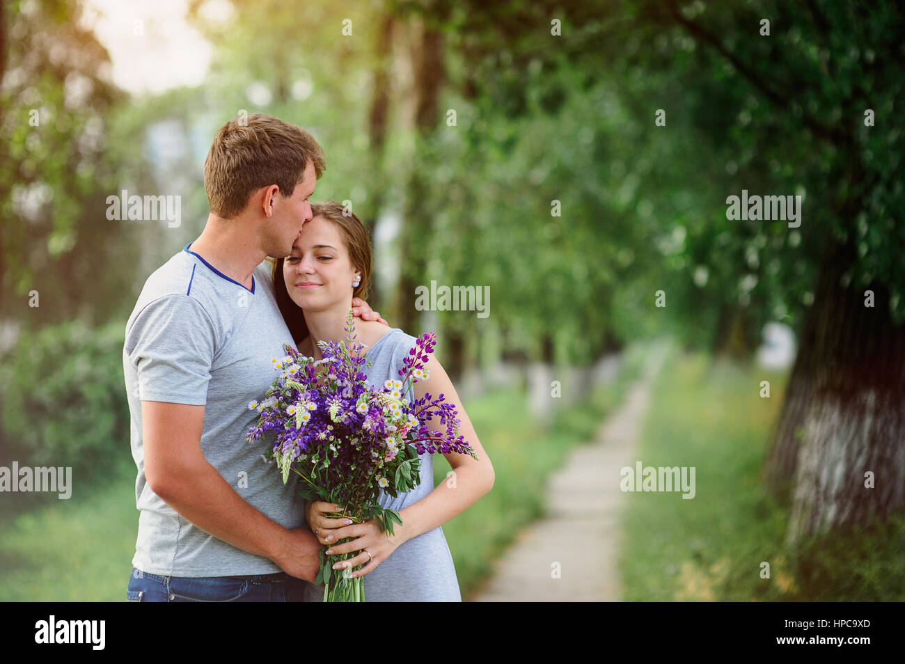 young couple in love with a bouquet of flowers on a background of the path Stock Photo