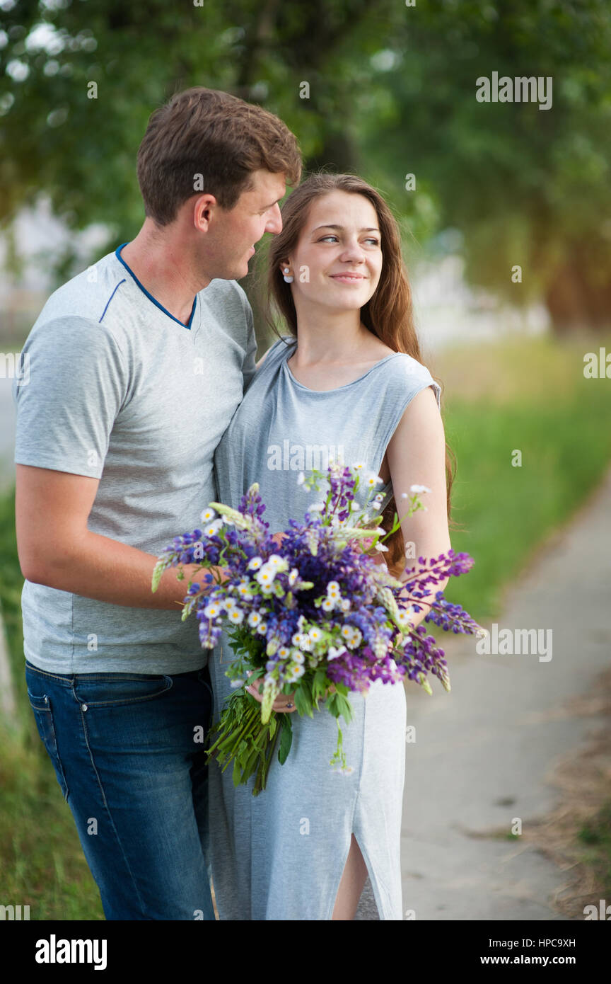 young couple in love with a bouquet of flowers on a background of the path Stock Photo