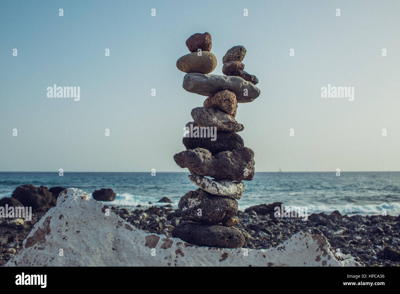 Stones stacked like a tower of equilibrium on 10 stories at the atlantic sea - tenerife Stone beach // Obstacles in life Stock Photo